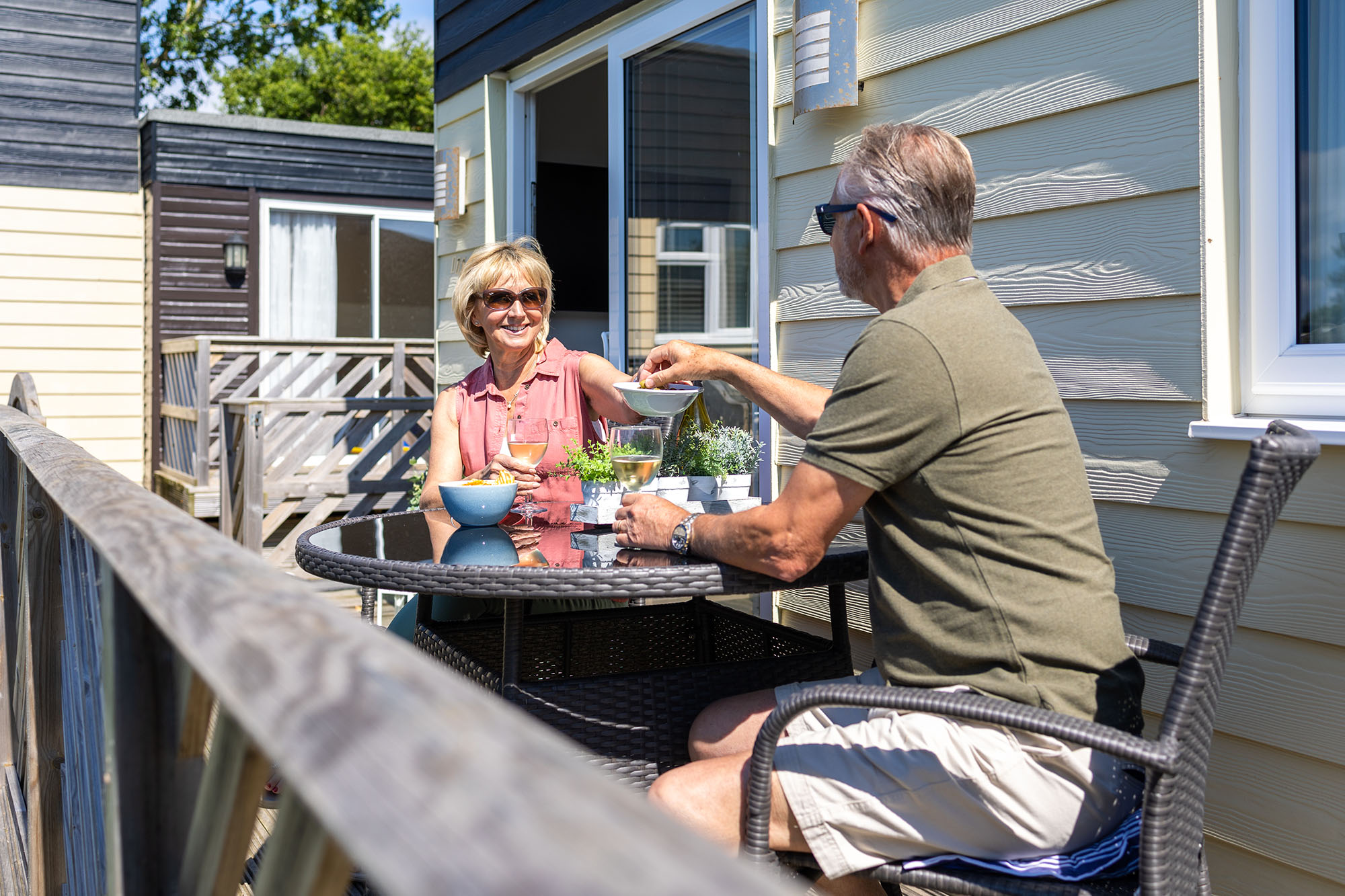 retired couple enjoy drinks on the decking of a classic chalet